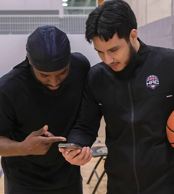 ali abo saada and an athlete looking at a phone during a basketball training session